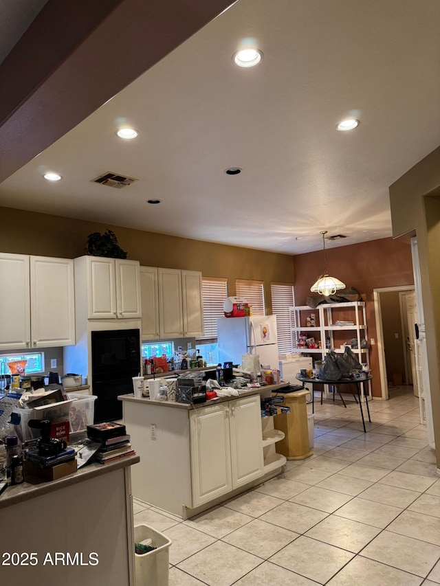 kitchen with pendant lighting, white fridge, white cabinetry, and black microwave