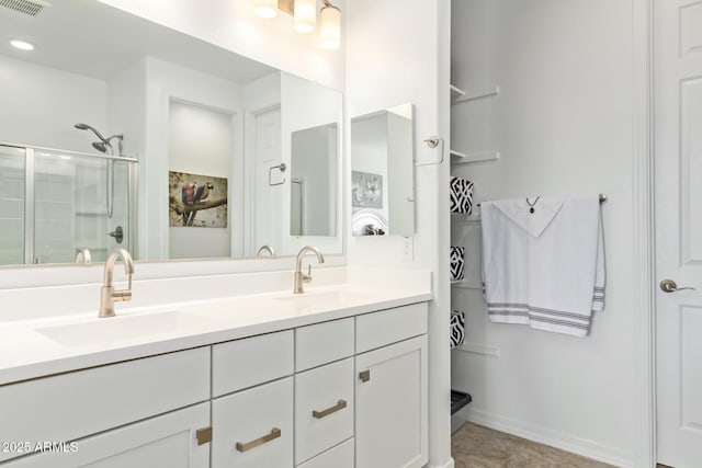 bathroom with a sink, visible vents, a stall shower, and double vanity