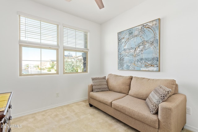 living area featuring a ceiling fan, light colored carpet, and baseboards