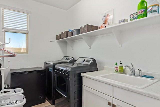 laundry room featuring a sink, cabinet space, light wood-style floors, and washing machine and dryer