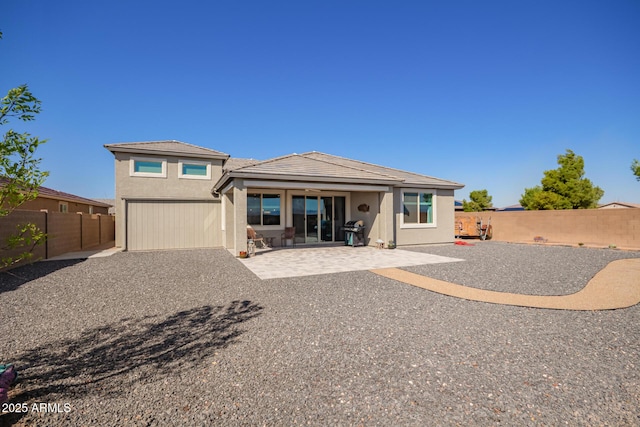 back of house featuring stucco siding, a patio, a fenced backyard, and an attached garage