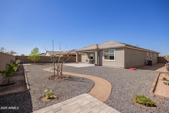 rear view of house with stucco siding, a patio, central AC unit, and a fenced backyard