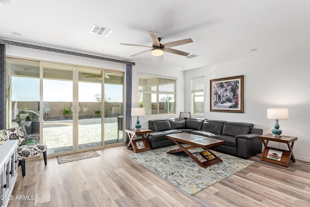 living room with light wood-style flooring, visible vents, and a wealth of natural light