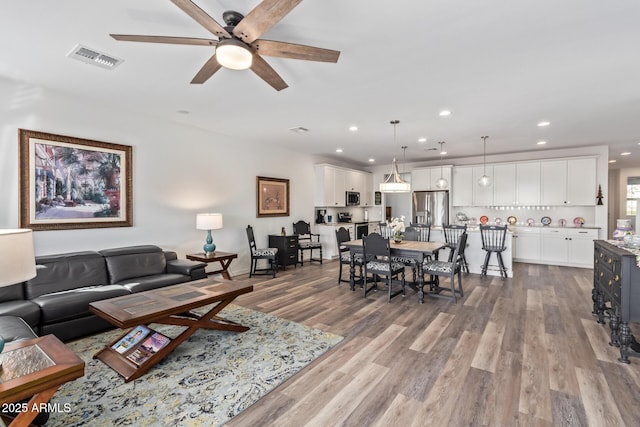 living area featuring visible vents, recessed lighting, ceiling fan, and wood finished floors