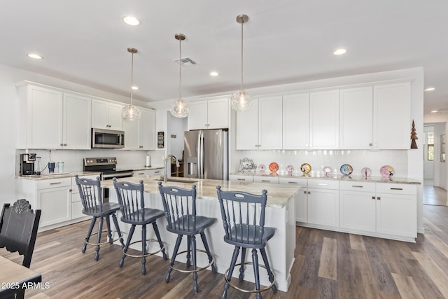 kitchen featuring stainless steel appliances, visible vents, a breakfast bar, and white cabinetry