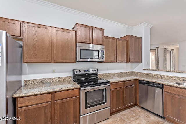 kitchen with light stone countertops, ornamental molding, appliances with stainless steel finishes, and sink