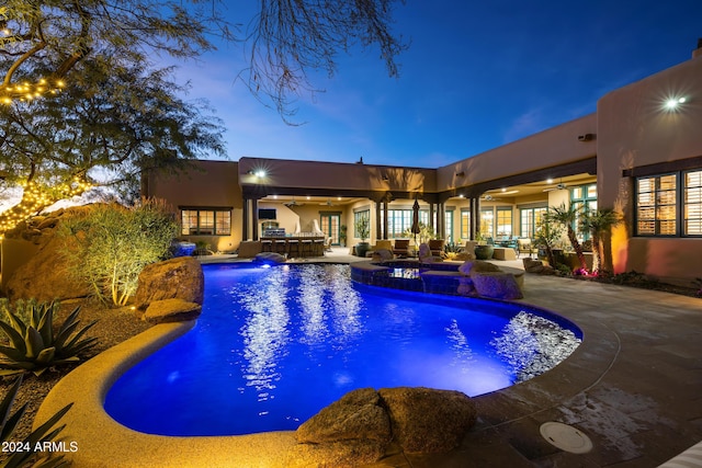 pool at dusk with a patio area, an in ground hot tub, outdoor lounge area, and exterior bar