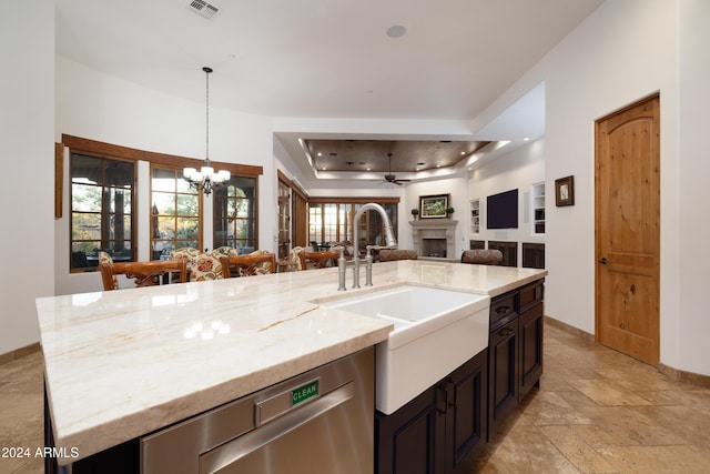 kitchen with a tray ceiling, a wealth of natural light, stainless steel dishwasher, and decorative light fixtures