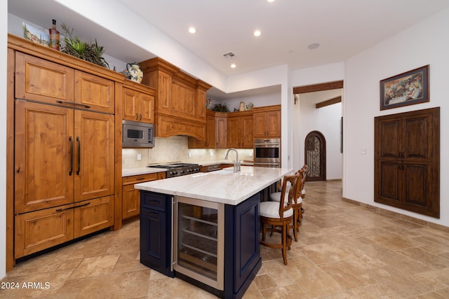 kitchen featuring an island with sink, tasteful backsplash, a breakfast bar area, beverage cooler, and stainless steel appliances