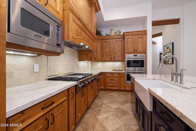 kitchen featuring sink, decorative backsplash, appliances with stainless steel finishes, light stone counters, and custom range hood