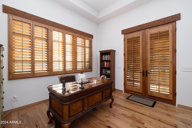 office with light wood-type flooring and french doors