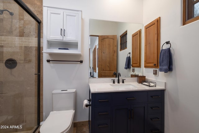 bathroom with vanity, toilet, and a shower with door