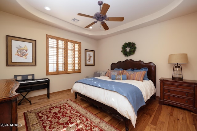 bedroom with a tray ceiling, ceiling fan, and hardwood / wood-style flooring