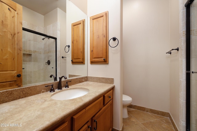 bathroom featuring tile patterned flooring, vanity, toilet, and a shower with door