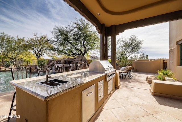 view of patio / terrace with an outdoor kitchen, a water view, sink, and grilling area