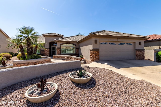 mediterranean / spanish house featuring an attached garage, a tile roof, concrete driveway, stone siding, and stucco siding