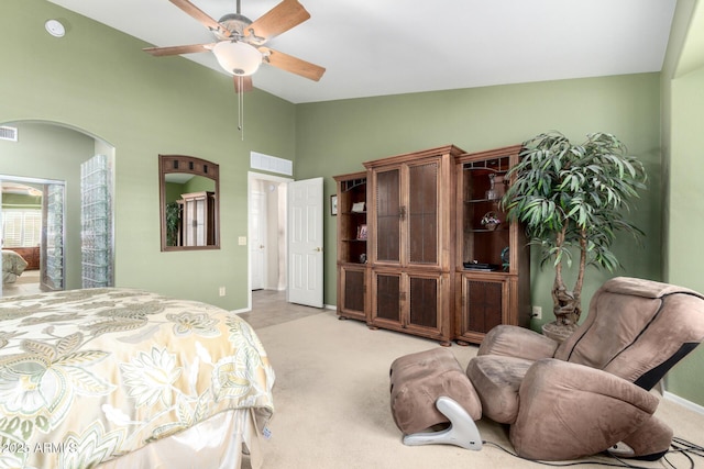 bedroom with arched walkways, light colored carpet, visible vents, and baseboards