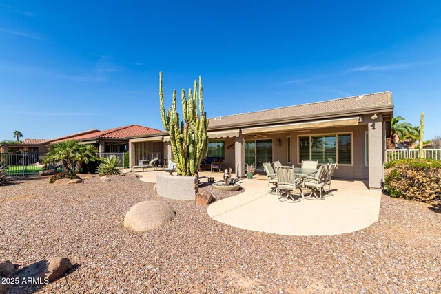 rear view of property featuring a tile roof, a patio area, fence, and stucco siding