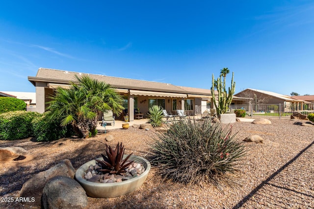 rear view of property featuring fence and a patio