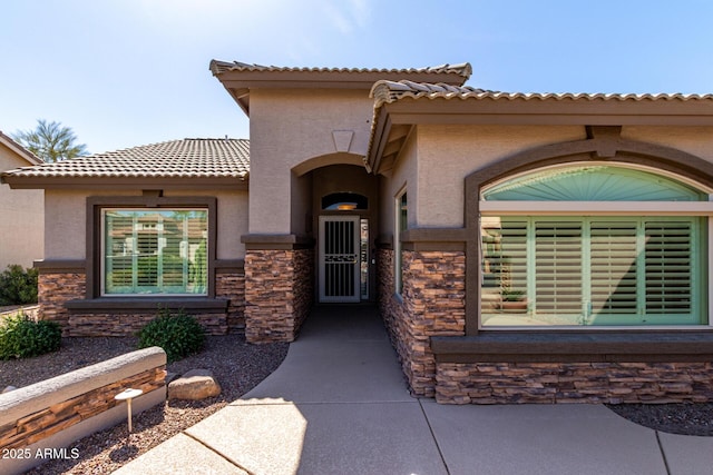 doorway to property with stone siding and stucco siding