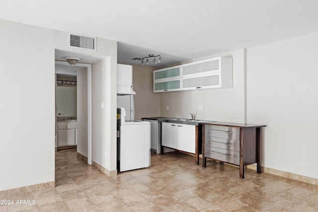 kitchen featuring washer / dryer and white cabinetry