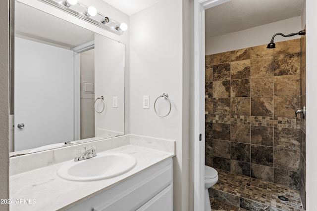 bathroom with vanity, toilet, and tiled shower