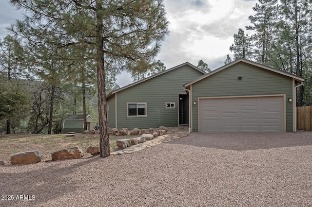 view of front of home featuring gravel driveway, an attached garage, and fence