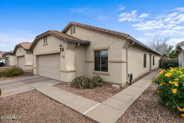 view of home's exterior featuring concrete driveway, an attached garage, a tile roof, and stucco siding