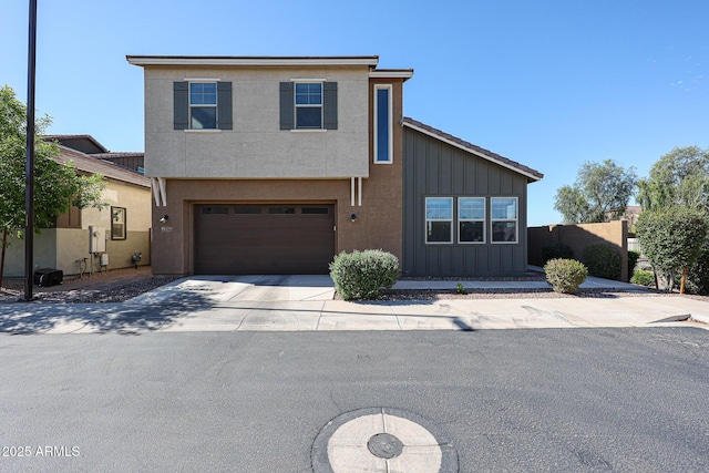 view of front of property with concrete driveway, fence, board and batten siding, and an attached garage