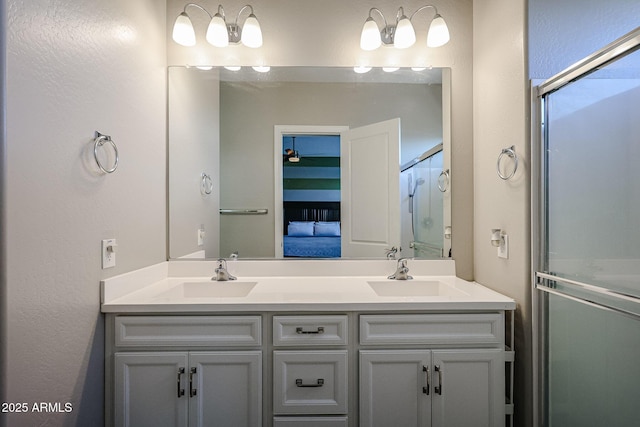 bathroom with double vanity, a shower with door, a sink, and ensuite bath