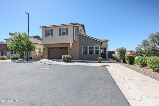 view of front facade featuring a garage, board and batten siding, fence, and concrete driveway