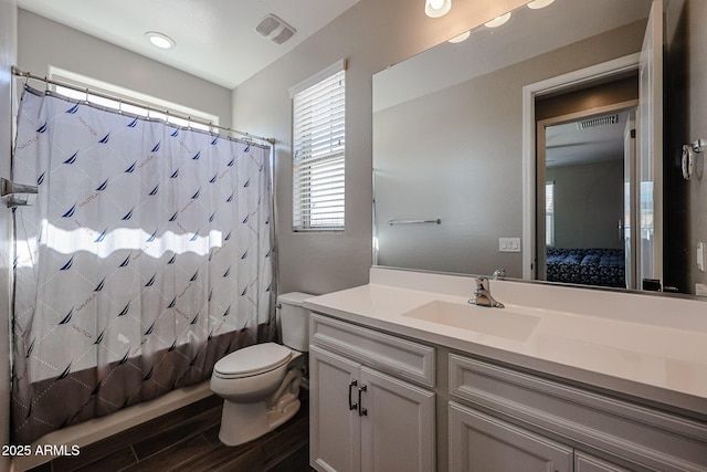 ensuite bathroom with connected bathroom, vanity, toilet, wood finished floors, and visible vents