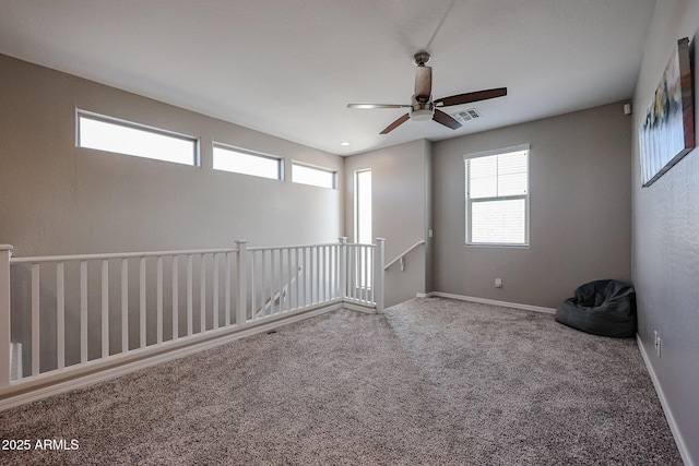 unfurnished room with carpet flooring, a ceiling fan, visible vents, and plenty of natural light