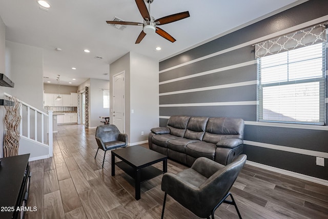 living area with a ceiling fan, baseboards, a healthy amount of sunlight, and wood finished floors