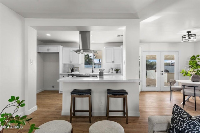 kitchen with french doors, white cabinetry, a kitchen breakfast bar, and hardwood / wood-style floors