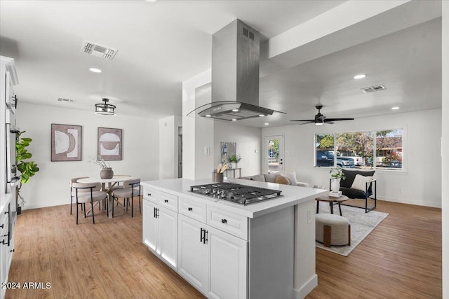 kitchen featuring stainless steel gas stovetop, white cabinetry, wall chimney range hood, and light hardwood / wood-style flooring