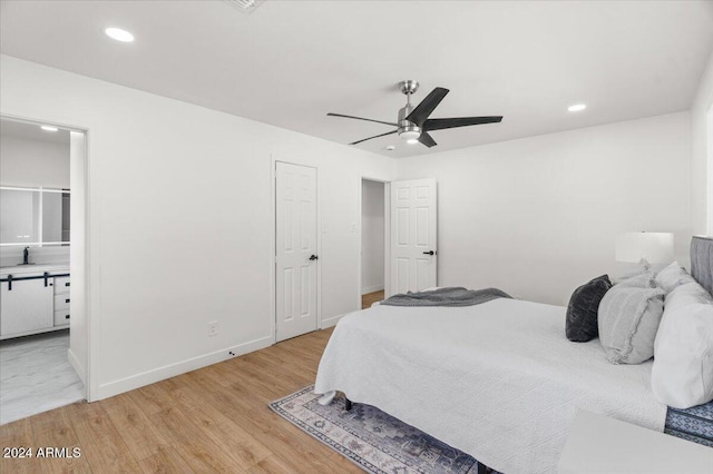 bedroom featuring light hardwood / wood-style flooring, ceiling fan, and sink