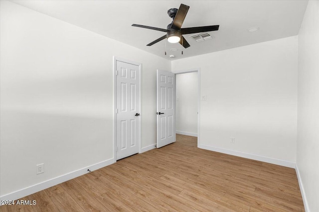 empty room with ceiling fan and light hardwood / wood-style flooring