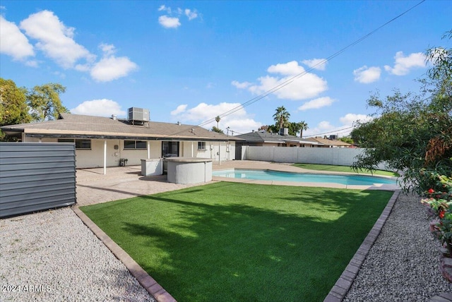 rear view of house with a yard, a fenced in pool, a patio, and central AC unit