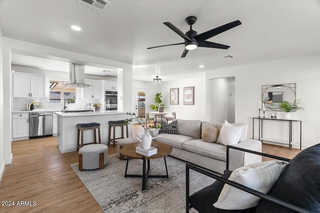 living room with ceiling fan, light wood-type flooring, and sink