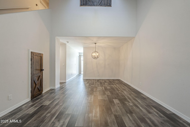 10101 N 91st Ave Unit 111, Peoria, AZ 85345 - unfurnished living room featuring dark wood-style floors, a chandelier, baseboards, and a high ceiling