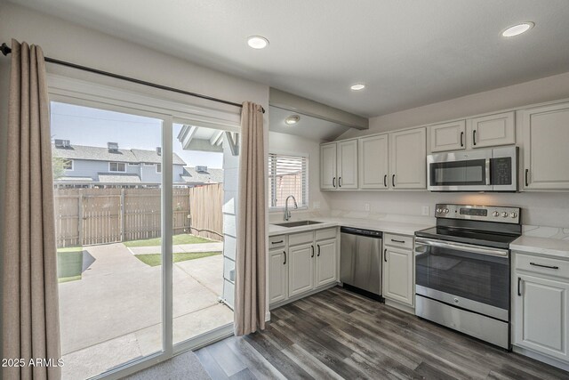 10101 N 91st Ave Unit 111, Peoria, AZ 85345 - kitchen with appliances with stainless steel finishes, lofted ceiling, a sink, dark wood finished floors, and white cabinetry