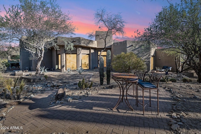 back house at dusk with a patio area