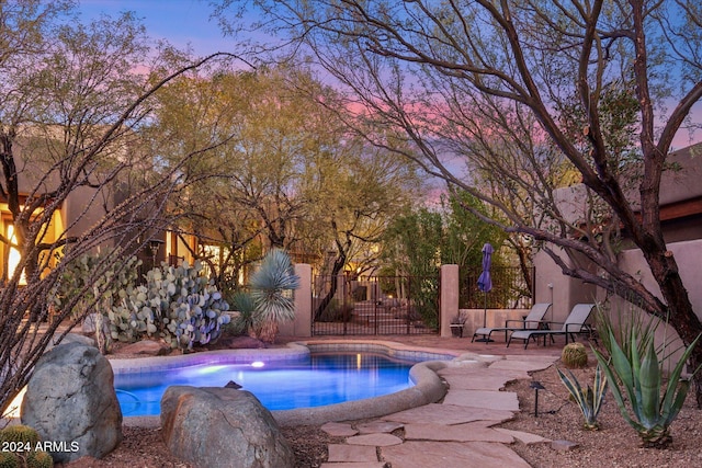 pool at dusk featuring a patio area