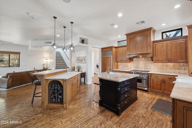 kitchen with a breakfast bar area, hardwood / wood-style flooring, a center island with sink, and high end appliances