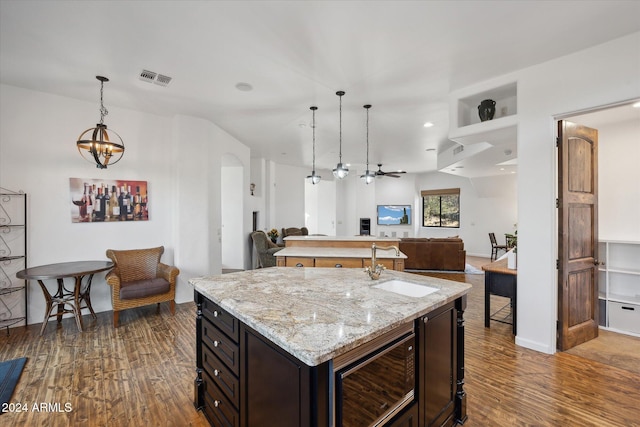 kitchen featuring built in microwave, sink, dark hardwood / wood-style flooring, dark brown cabinets, and a center island with sink