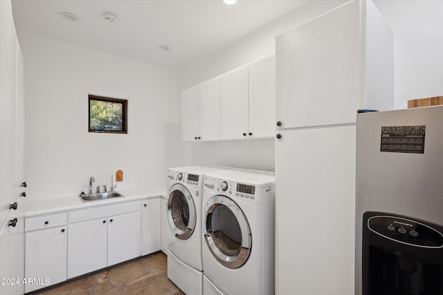 washroom with cabinets, independent washer and dryer, and sink