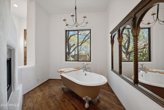 bathroom featuring a chandelier, a tub to relax in, and hardwood / wood-style flooring