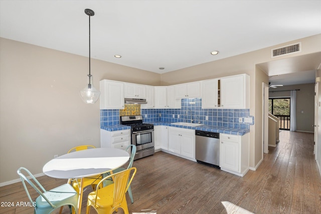 kitchen with white cabinets, dark hardwood / wood-style flooring, hanging light fixtures, and appliances with stainless steel finishes