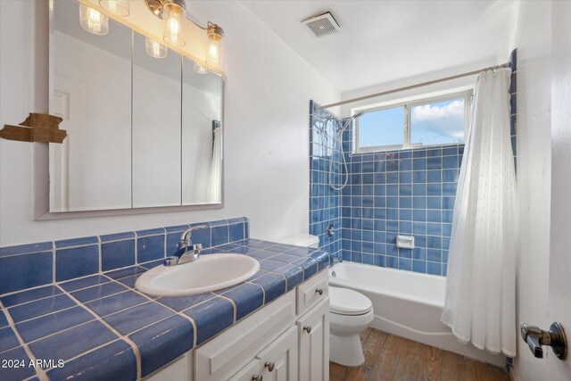 full bathroom with decorative backsplash, shower / tub combo, vanity, hardwood / wood-style flooring, and toilet